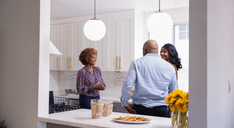 Three people discussing home buying opportunities in a bright, modern kitchen.
